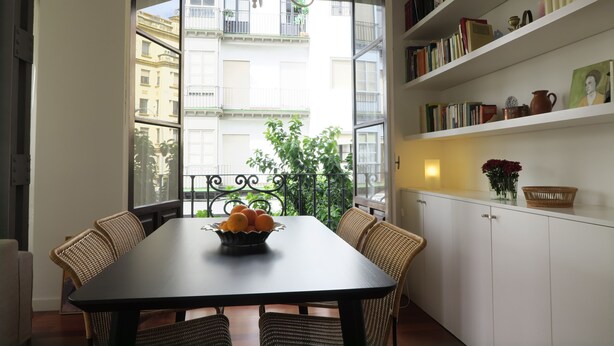 A dining area with a table, chairs, a bowl of fruit, and a bookshelf. - Amazing Apartment in Regionalist building (Sevilla)