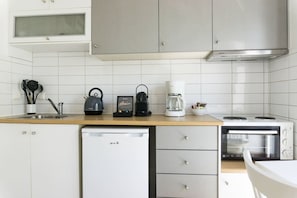 A modern kitchen with a dishwasher, a coffee maker, a kettle, and a microwave.