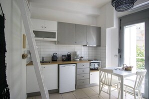 Een kleine keuken met een vaatwasser, waterkoker, koffiezetapparaat en oven.