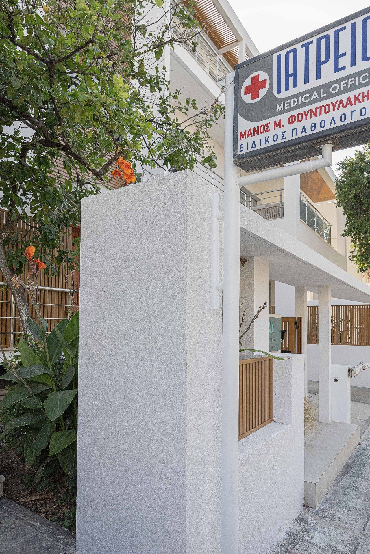 A medical office building with a signboard, a white exterior wall, and a staircase leading to an upper level.