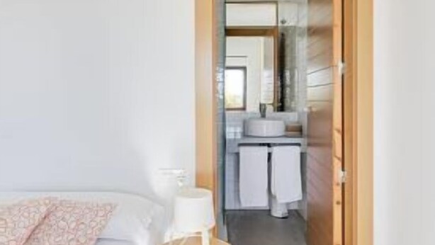 A bedroom with a bed, a small stool, and a nightstand.