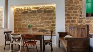 A dining area with a stone wall, wooden table, and chairs.