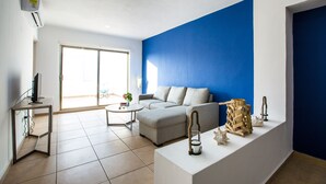 A modern living room with a grey sofa, a small coffee table, and a white console table with decorative items. - Central Amazing PH with Private Rooftop and Jacuzzi (Playa del Carmen)