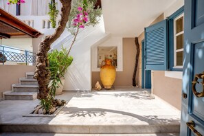 A courtyard with a large vase, steps leading to a door, and a tree with flowers.