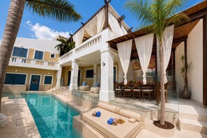 A poolside area with a lounge chair, a table with chairs, and a pool.