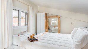 A bedroom with a large bed, a bedside table with a basket and a glass of orange juice, and a window with curtains. - Villa Kallergi - Athena (640 m2) - north-western Crete with Concert Piano & Pool (Rethymnon)