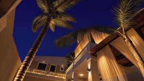 A building with a balcony and palm trees at dusk. - Villa Kallergi - Athena (640 m2) - north-western Crete with Concert Piano & Pool (Rethymnon)