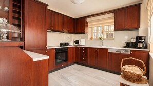 A modern kitchen with wooden cabinets, a built-in oven, a microwave, and a coffee maker. - Villa Kallergi - Athena (640 m2) - north-western Crete with Concert Piano & Pool (Rethymnon)