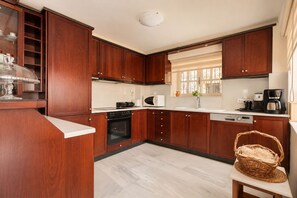 A modern kitchen with wooden cabinets, a built-in oven, a microwave, and a coffee maker. - Villa Kallergi - Athena (640 m2) - north-western Crete with Concert Piano & Pool (Rethymnon)