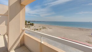 Een balkon met uitzicht op een strand en een verre stadshemel.