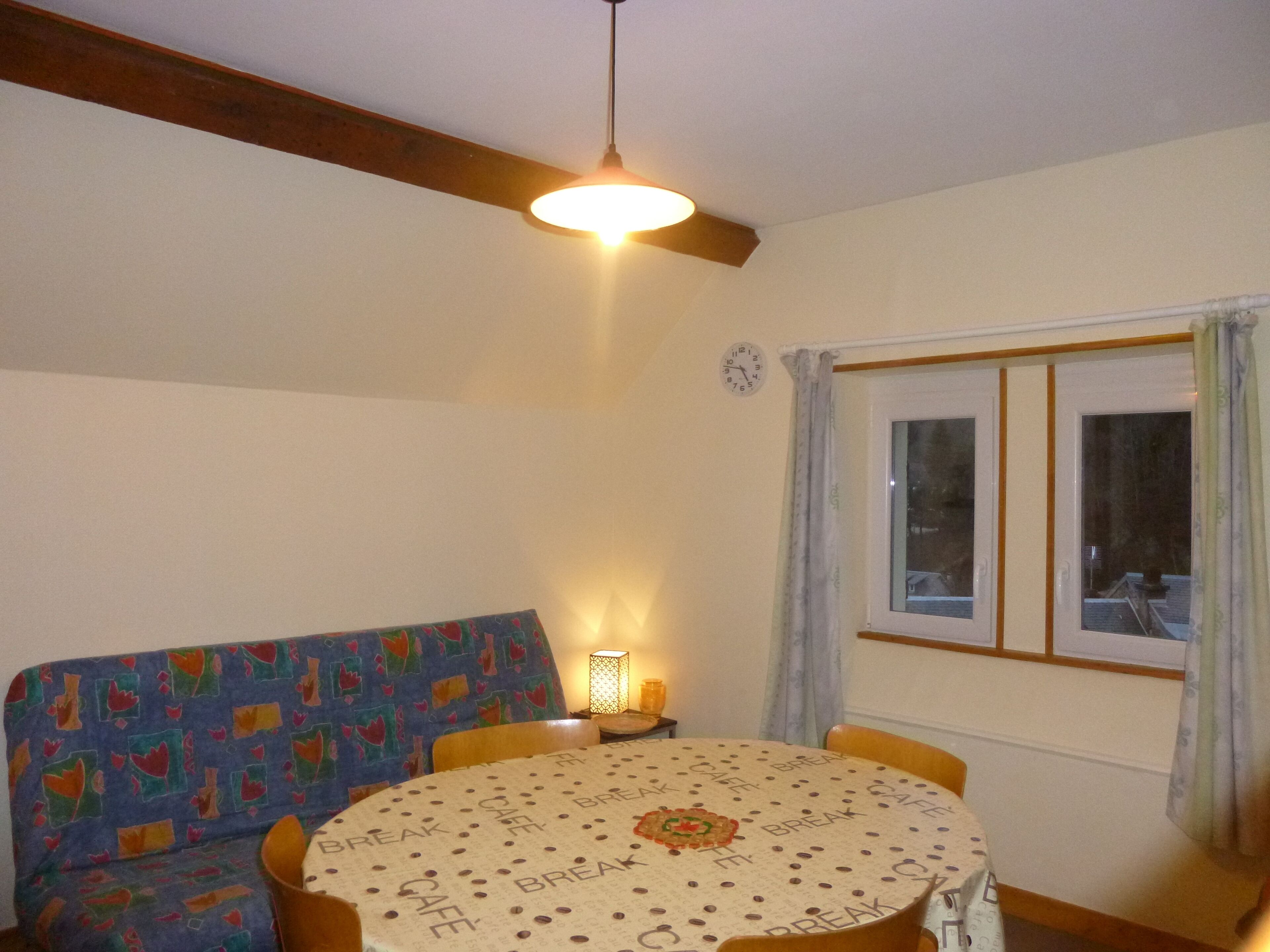 A cozy room with a round table, a sofa, and a window with curtains.