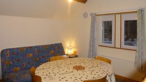 Una habitación acogedora con una mesa redonda, un sofá y una ventana con cortinas.