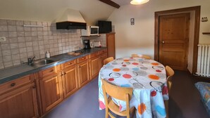 Una cocina compacta con armarios de madera, microondas integrado y una mesa de comedor con mantel colorido.