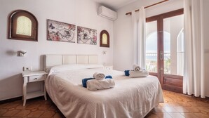 Habitación de hotel con cama, escritorio, aire acondicionado de pared y ventana con cortinas.