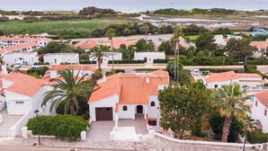 Una zona residencial costera con edificios blancos, techos de tejas rojas y palmeras.