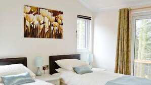 Ein Hotelzimmer mit zwei Betten, einem Vorhangfenster und einem Bild an der Wand.