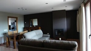 Een moderne woonkamer met een bank, een eettafel en een open haard.