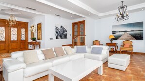 Un salon spacieux avec un canapé d’angle blanc, une table basse et un escalier en bois.