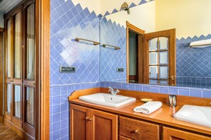 Une salle de bain avec un meuble-lavabo en bois, un lavabo blanc et un mur recouvert de carreaux bleus.