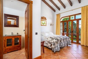 Une chambre à coucher avec un lit, une armoire en bois, un miroir et une fenêtre avec des rideaux.