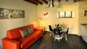 A modern living room with a red sofa, a dining table with chairs, and a kitchen area. - Rural apartment Casona la Sierra for 4 people (Cudillero)