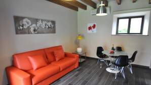 A modern living room with a red sofa, a dining table with chairs, a vase, and artwork on the walls. - Rural apartment Casona la Sierra for 4 people (Cudillero)