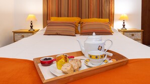 A neatly made bed with striped pillows, a tray with breakfast items, and a teapot on a wooden tray. - Casa do Loreto - Ponta Delgada (Fajã de Baixo)