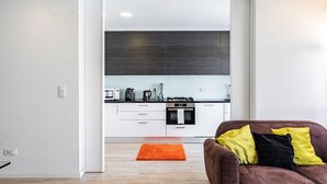A modern kitchen with white cabinets, a black oven, and a stainless steel range hood.