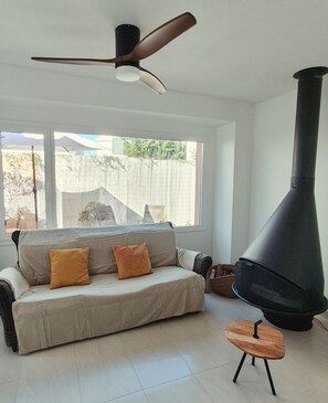 A modern living room with a sofa, a small table, a large chimney, and a ceiling fan. - Nice villa with wonderful sights, come to profite sunrise on the ser (Torredembarra)