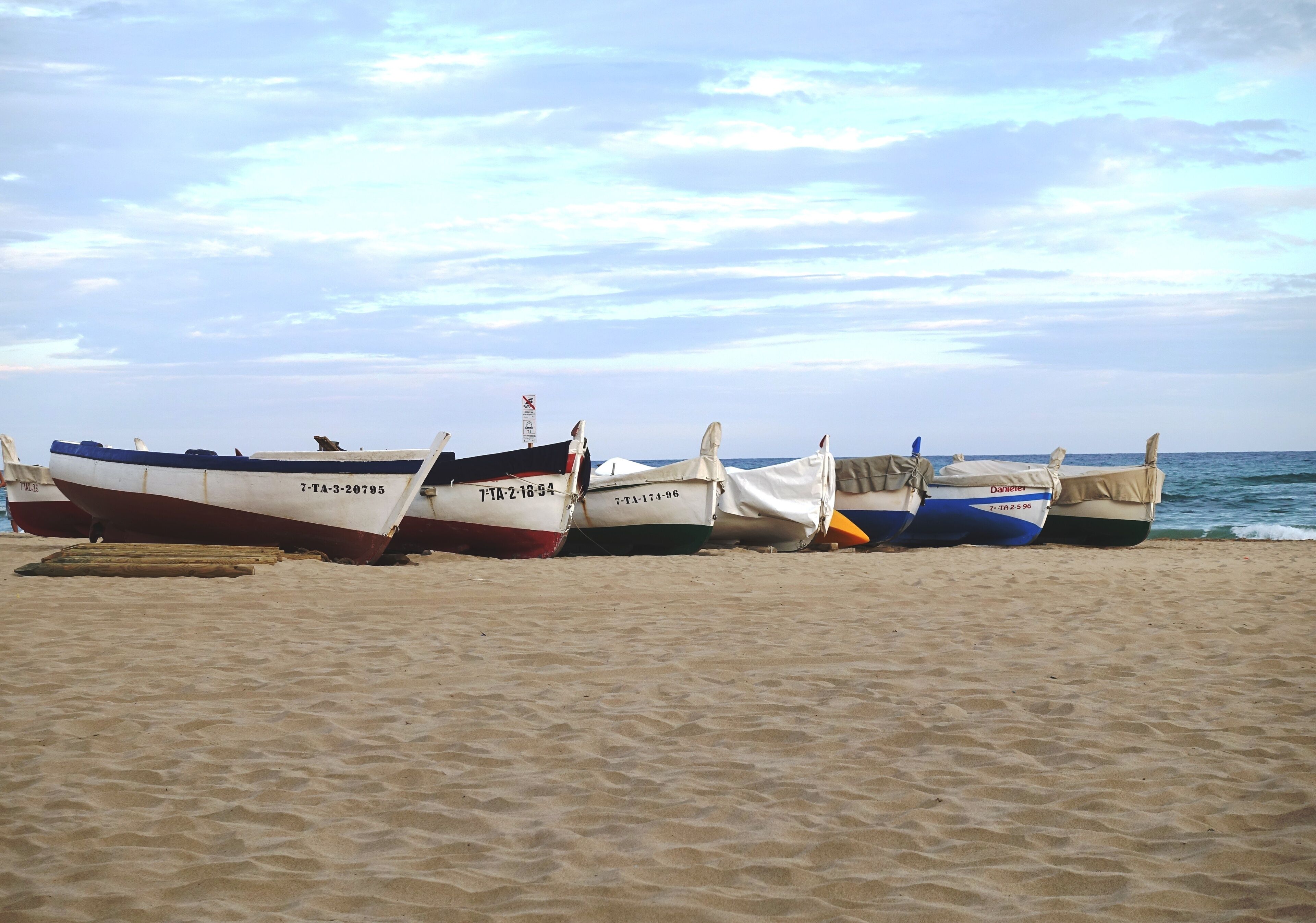Plusieurs bateaux étaient alignés sur une plage de sable, avec l’océan en toile de fond.