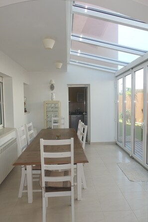 A dining area with a wooden table and white chairs, a glass cabinet, and a kitchen visible through an open door. - Nice villa with wonderful sights, come to profite sunrise on the ser (Torredembarra)