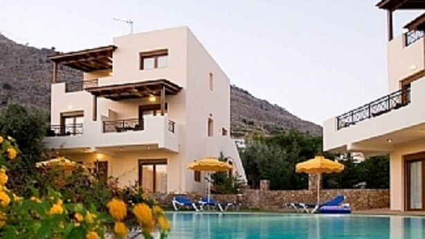 Et moderne hotel med pool, altaner og gule parasoller.