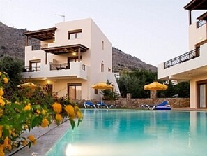 A modern hotel with a pool, balconies, and yellow umbrellas.