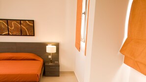 Et moderne hotelværelse med seng, sengebord, lampe og en pyntende plante.