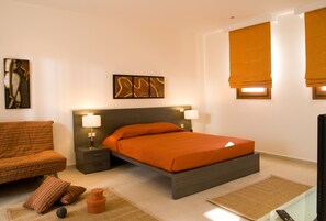A modern bedroom with a bed, nightstands, a sofa, and artwork on the walls.
