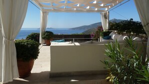 A covered outdoor seating area with a view of the sea and hills. - Apartment With Shared Pool And Sea Views (Kalkan)
