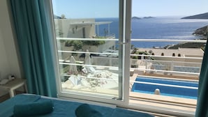 A hotel room with a large window overlooking a pool and the sea. - Apartment With Shared Pool And Sea Views (Kalkan)