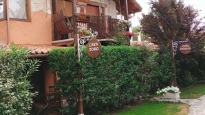 A rustic wooden house with a balcony and a stone pathway leading to it.