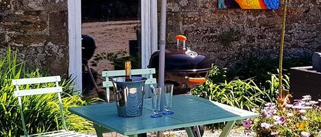 An outdoor patio with a table and chairs, a green umbrella, and a mural of a parrot on the wall.