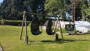A swing set in a park with a mural in the background. - Beautiful, spacious, 2 bed renovated breton cider press, 10km from the coast! (Cast)