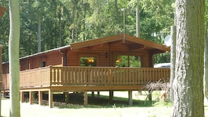 Une cabane en bois dotée d’un balcon, entourée d’arbres.