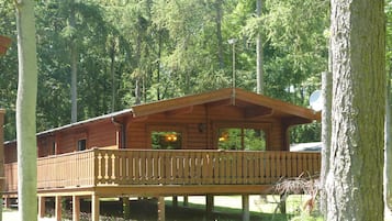 Standalone cabin surrounded by a forest, offering a simple, functional design with a flat roof and balcony.