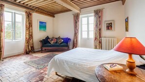 Ein Schlafzimmer mit einem Bett, einer Holzbalkendecke, einer Couch und einer Heizung.