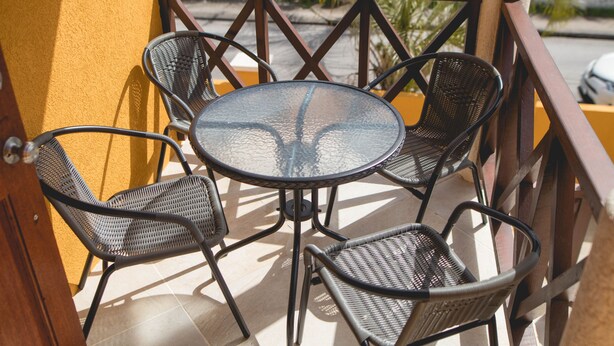 A balcony with a round table and four chairs. - Frontline apartment No. 2 (Oistins)