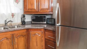 A kitchen with wooden cabinets, stainless steel appliances, and a granite countertop. - Frontline apartment No. 2 (Oistins)