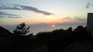 A sunset over a body of water with silhouettes of trees and a building in the foreground. - 2 ROOMS FOR RENT TWO STEPS FROM THE SEA (Ault)