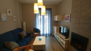 Ett vardagsrum med en blå soffa, ett litet bord, en tv och en öppen spis.