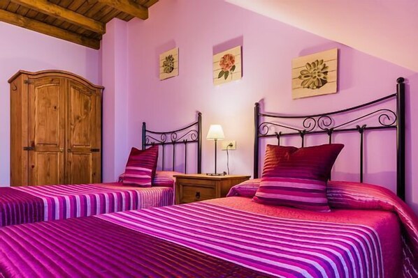 A bedroom with two beds, wooden wardrobe, and floral wall art. - Rural apartment L'Abiseu for 4 people (Villablino)