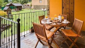 Een balkon met een ontbijt-opstelling, met uitzicht op een bergachtig landschap.