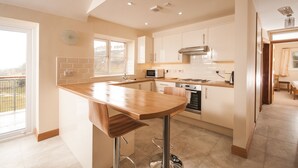 A modern kitchen with a central island, stainless steel appliances, and a view to the outside.